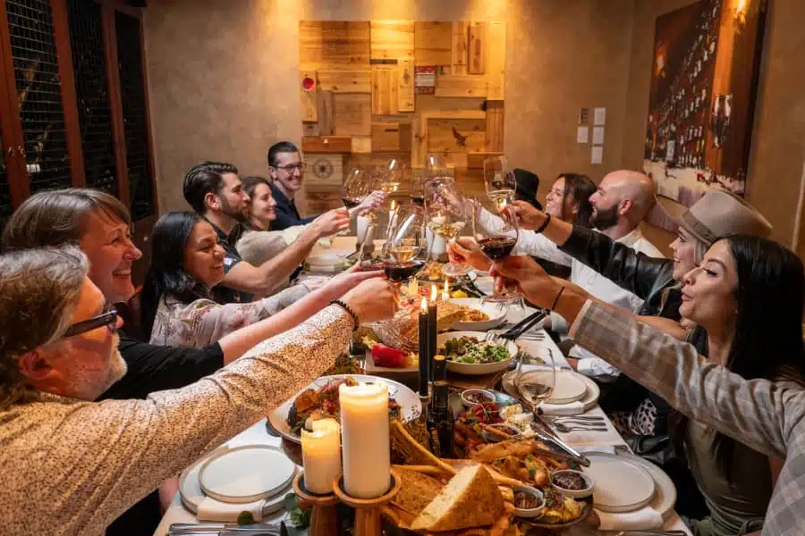 Group of friends eating Italian food and clinking wine glasses