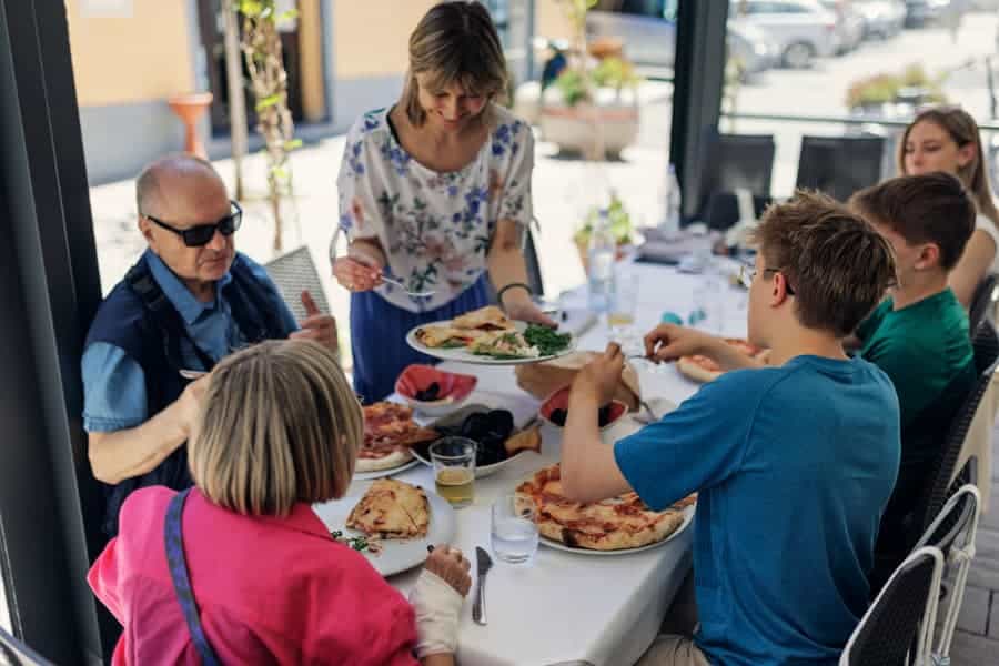 Family enjoying eating pizza for lunch in Italian restaurant