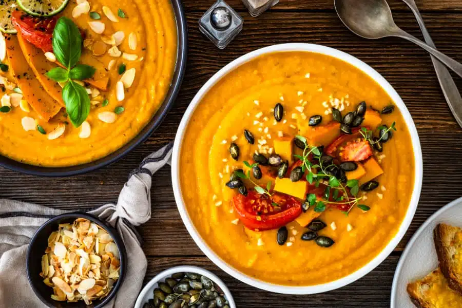 Bowls of pumpkin cream soup on wooden table