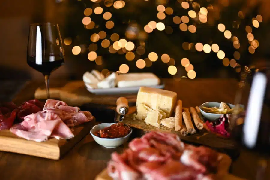 Charcuterie board spread with wine and Christmas lights